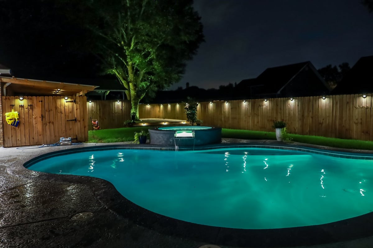 Backyard swimming pool at night with colorful lighting