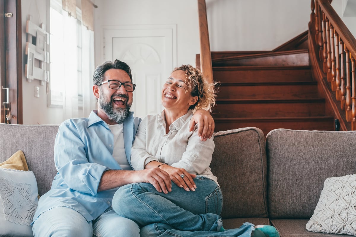Happy Caucasian couple laughing while sitting on sofa customer review