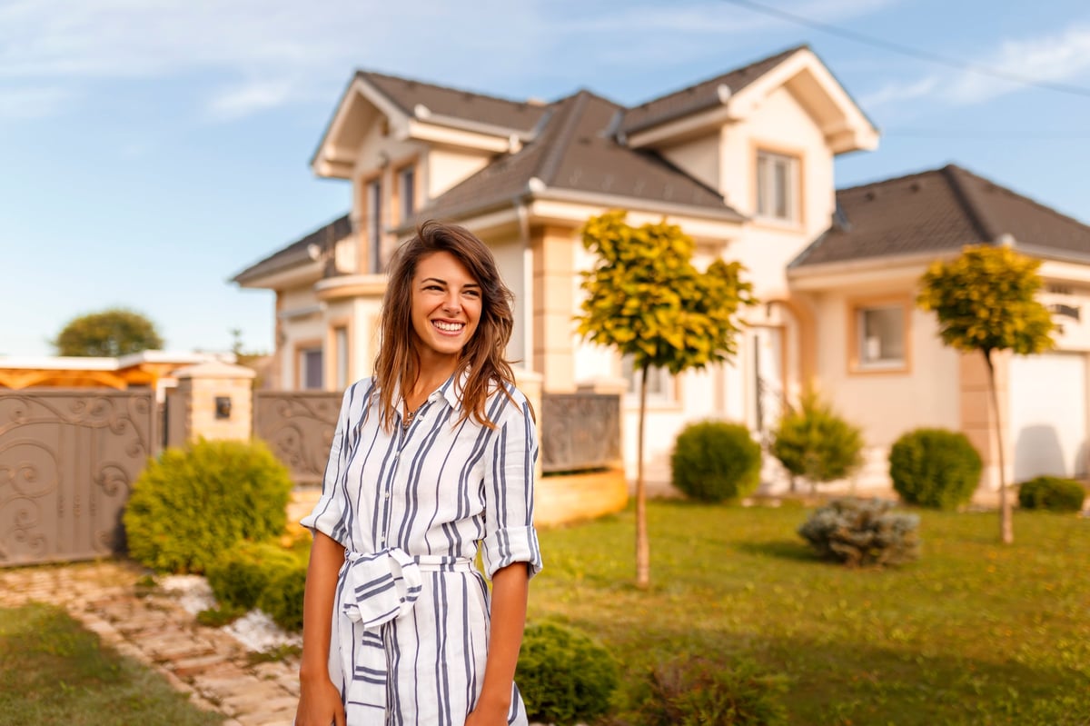 Beautiful young woman standing in front of her new house customer review