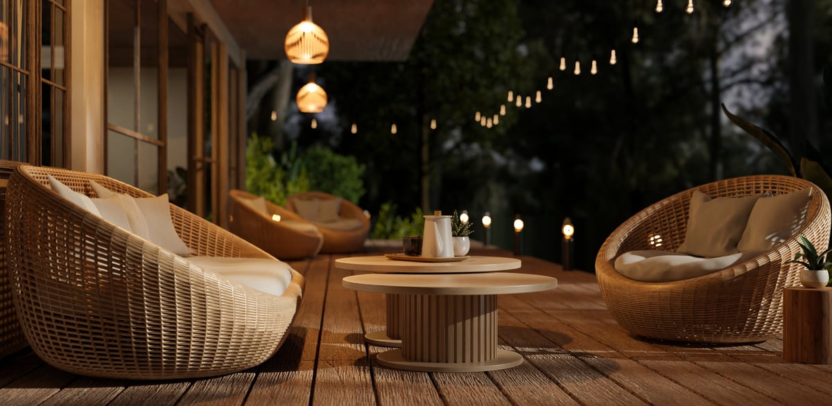 Beautiful deck with wicker armchairs and outdoor string lights at night