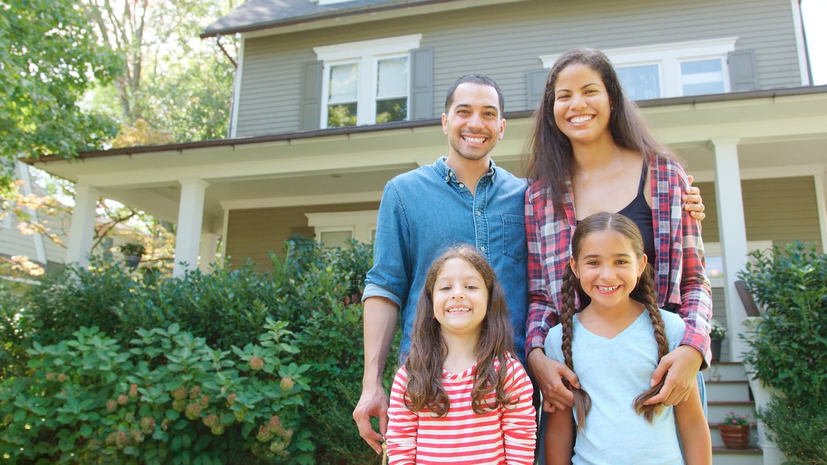 Smiling family standing in front of their illuminated home