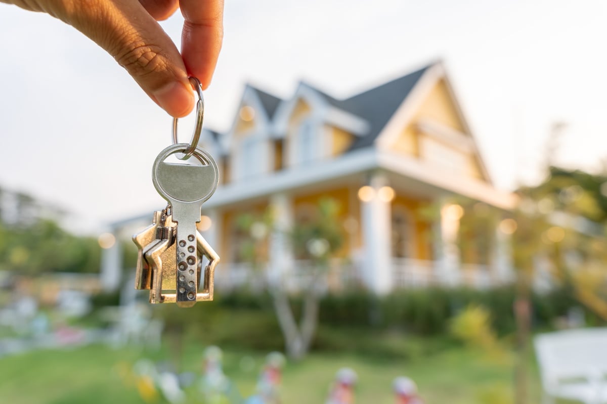 Smiling agent holding a key for a new homeowner customer review