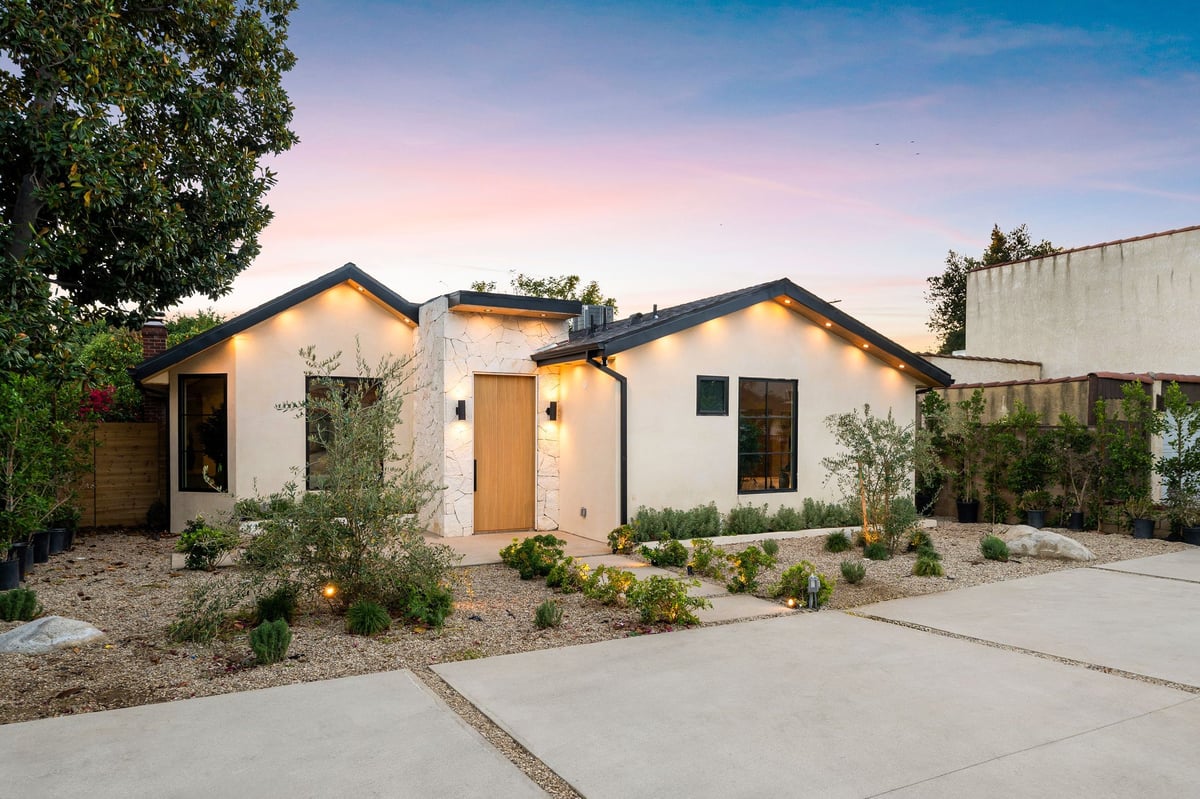 Modern single-story house with landscaped front yard at sunset