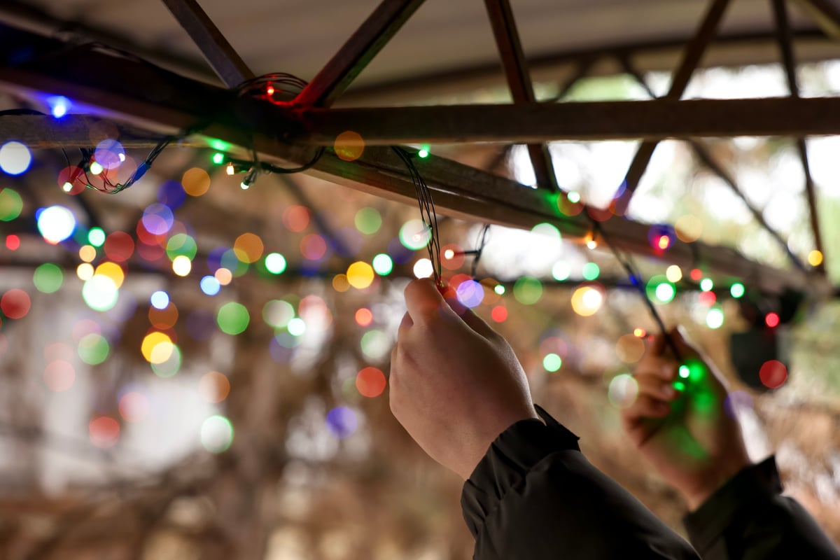 Man decorating house with Christmas lights outdoors closeup