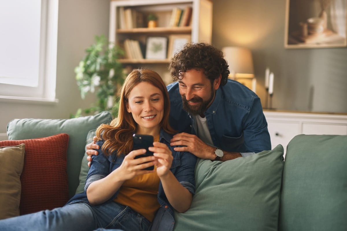 Couple sharing a tender moment while using a smartphone at home customer review