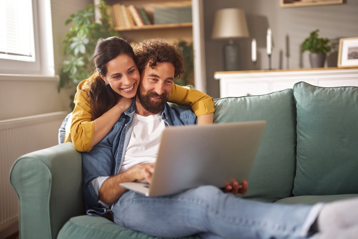 Smiling couple relaxing and using laptop at home customer review