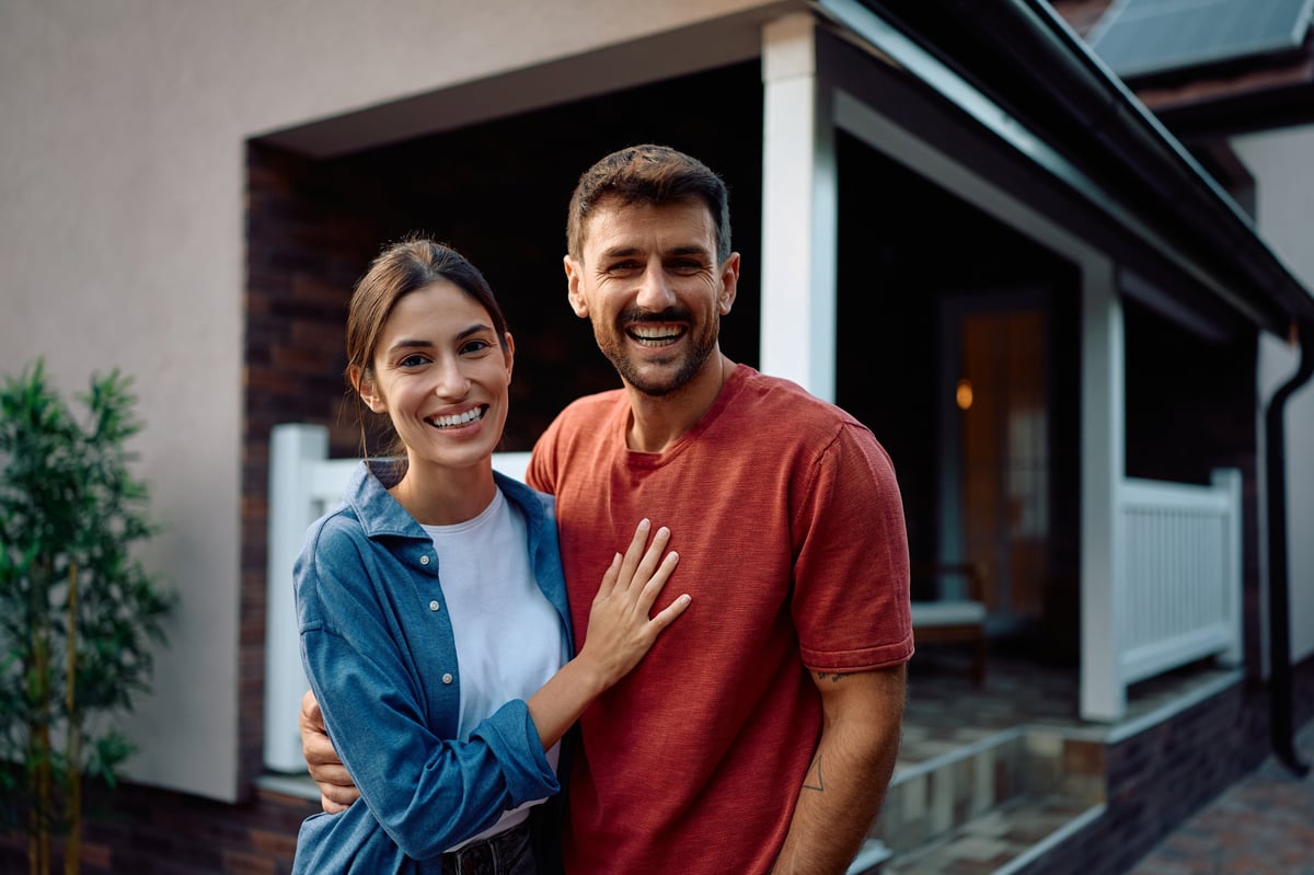 Happy couple standing in front of their new home customer review