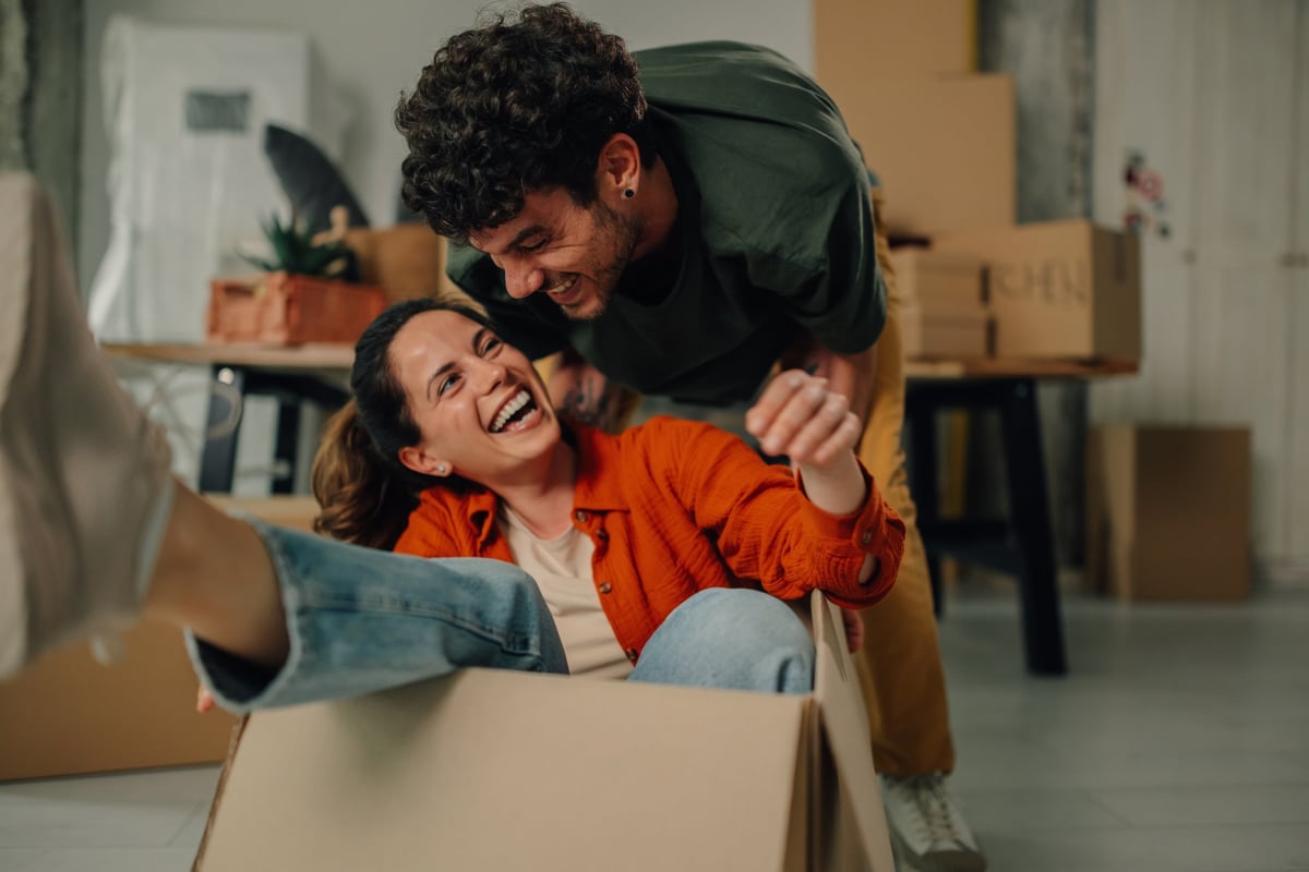 Young couple laughing and playing while settling into a new apartment customer review