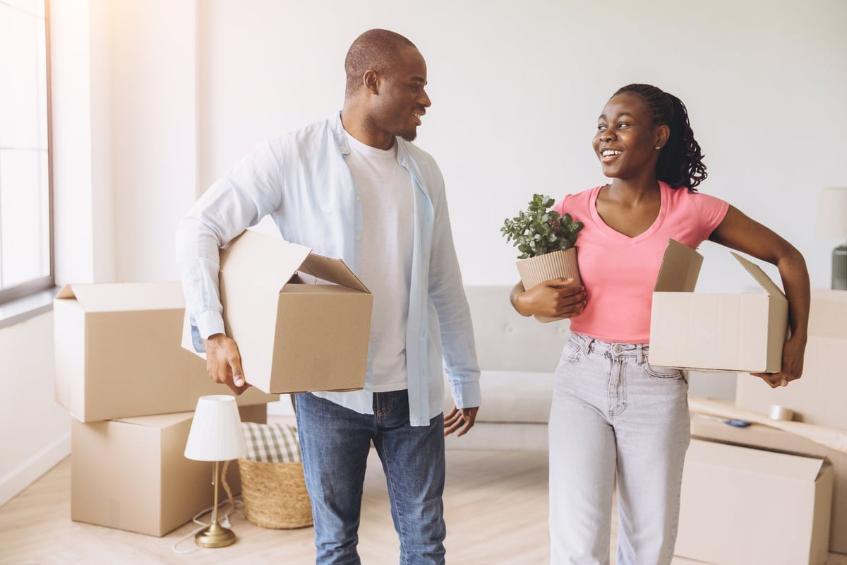 Young couple carrying boxes and a plant relocating happily customer review