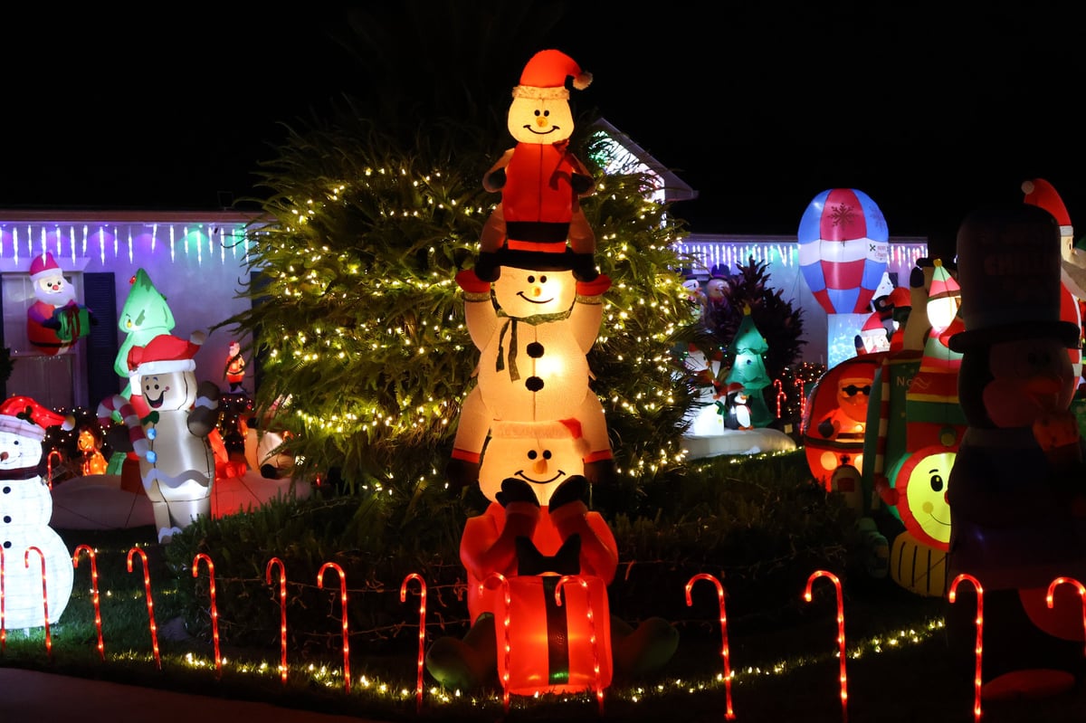Festive Christmas decoration display with snowman, Santa, and lit tree at night