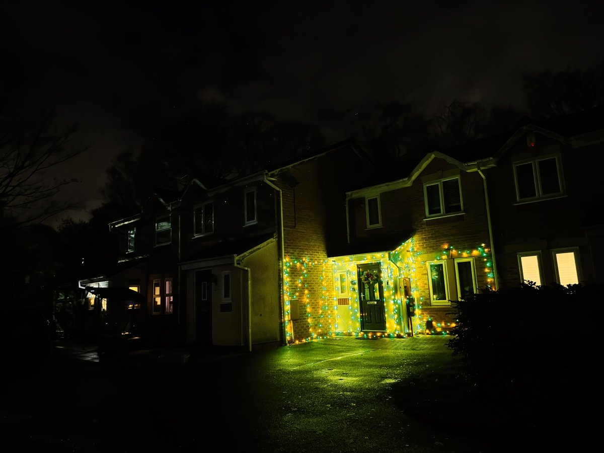 Manchester row house with colorful Christmas lights and a glowing front doorway