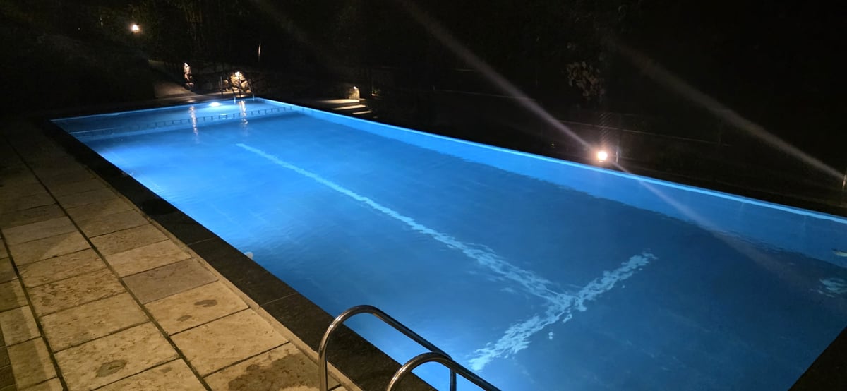 Long rectangular pool softly lit along the edges at night