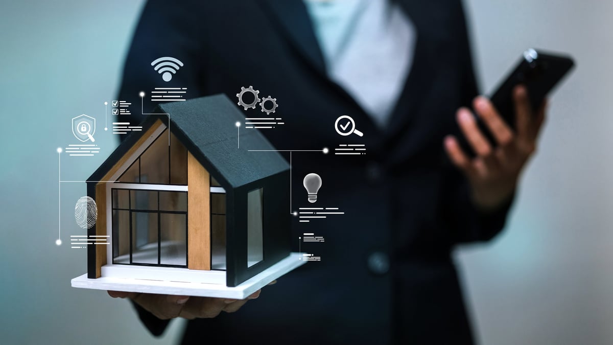 Businessman holding a modern house model with smart home automation icons