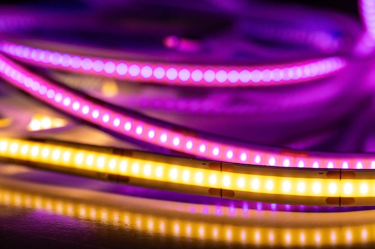 Close-up of colorful LED strip lights glowing in purple and warm white tones with reflections