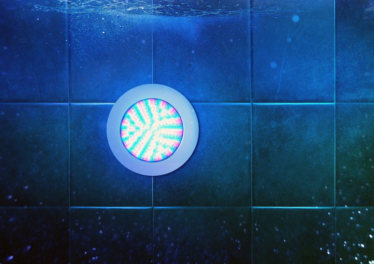 Circular underwater LED pool light glowing against dark blue tiles