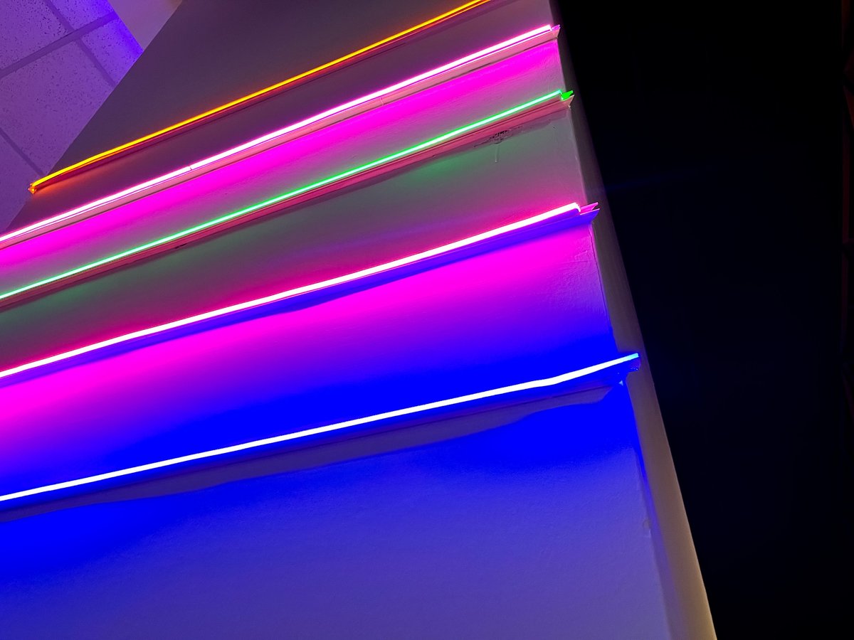 Abstract background with bright neon light lines in pink, green, orange, and blue