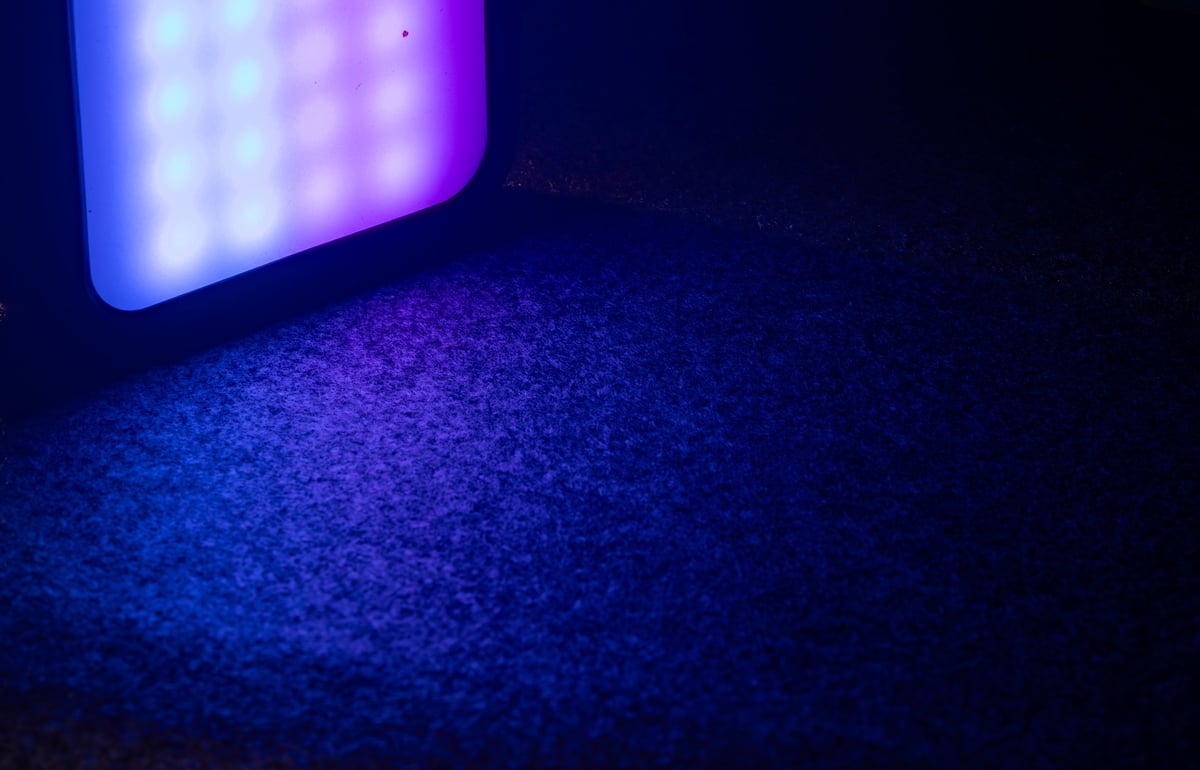 Multi-color LED video light illuminating a dark backdrop with vibrant neon tones