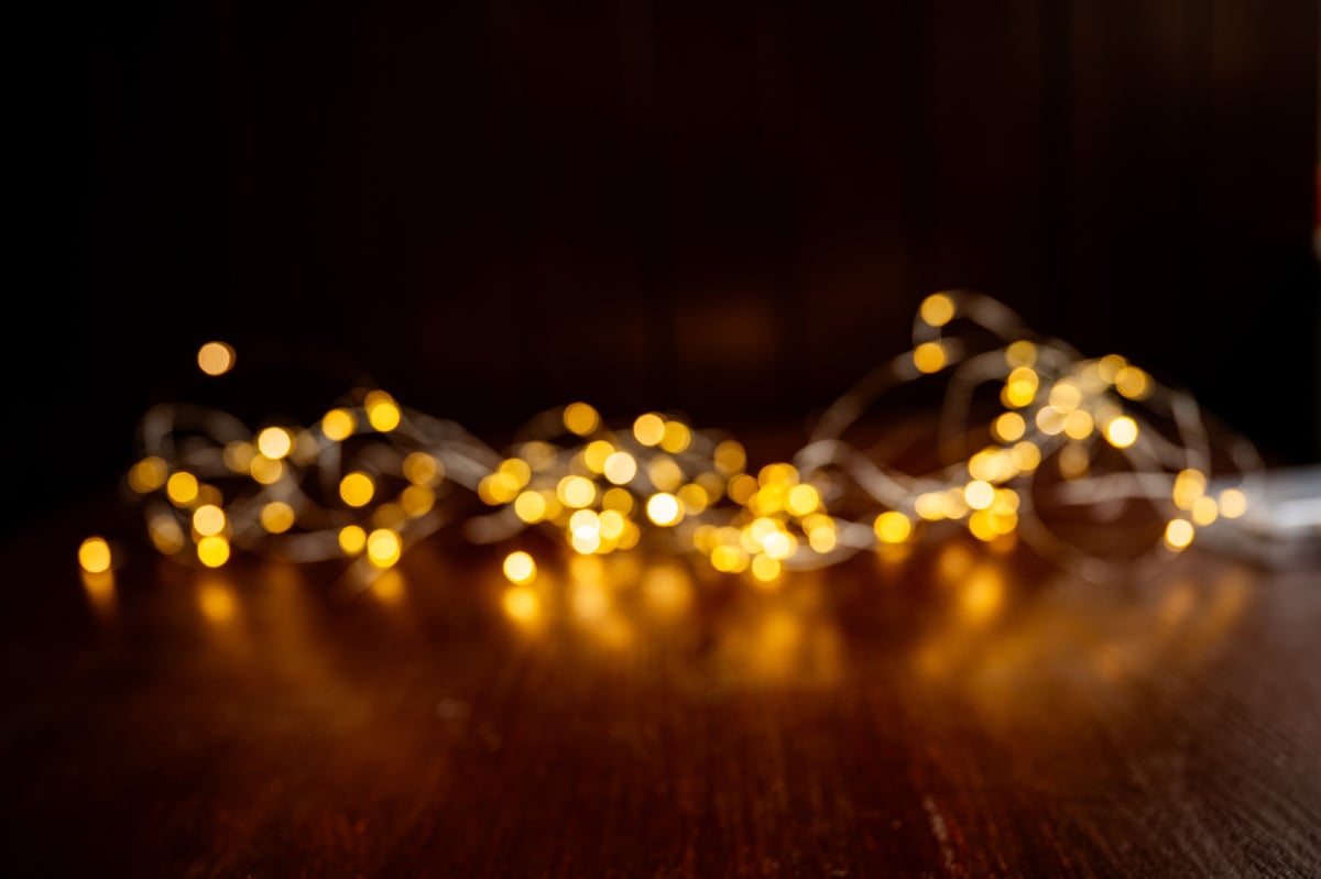Golden string lights creating a warm and festive bokeh effect on dark wooden surface