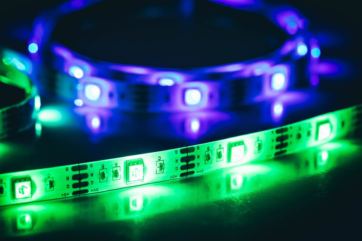 Close up of green and purple illuminated LED strip lights on a reflective surface