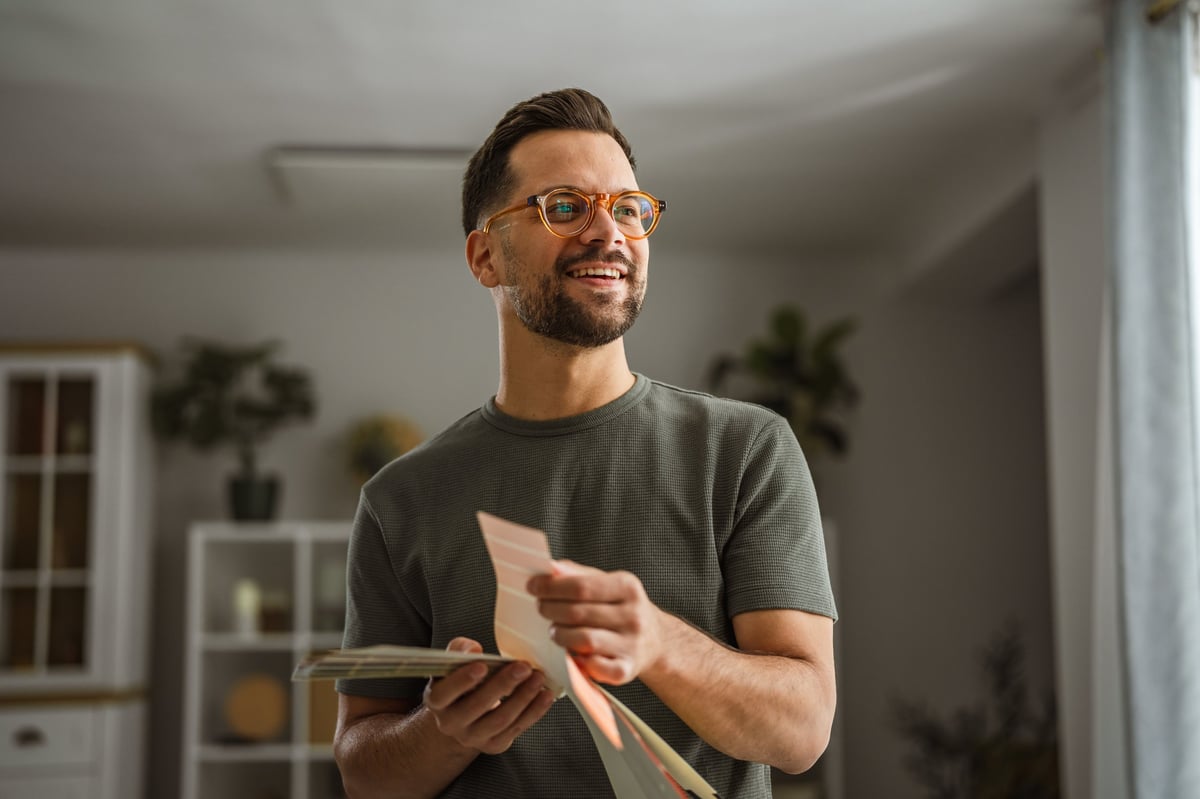 Smiling man holding color swatches making a design decision customer review