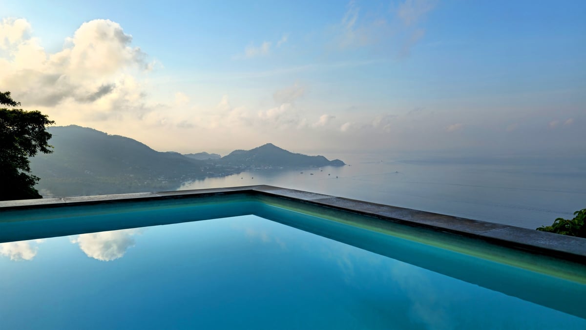 Infinity swimming pool overlooking a tropical bay at sunset