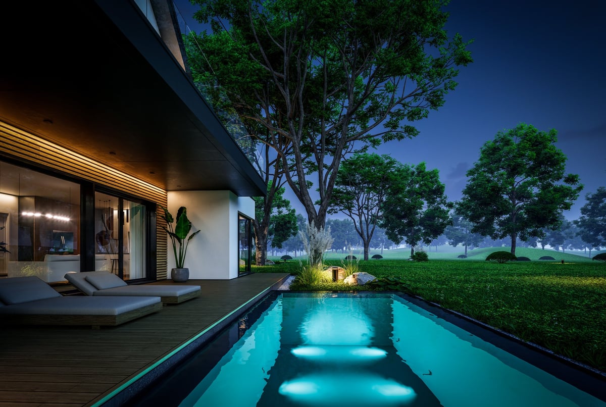 Contemporary luxury house exterior with dramatic patio and garden lighting at night