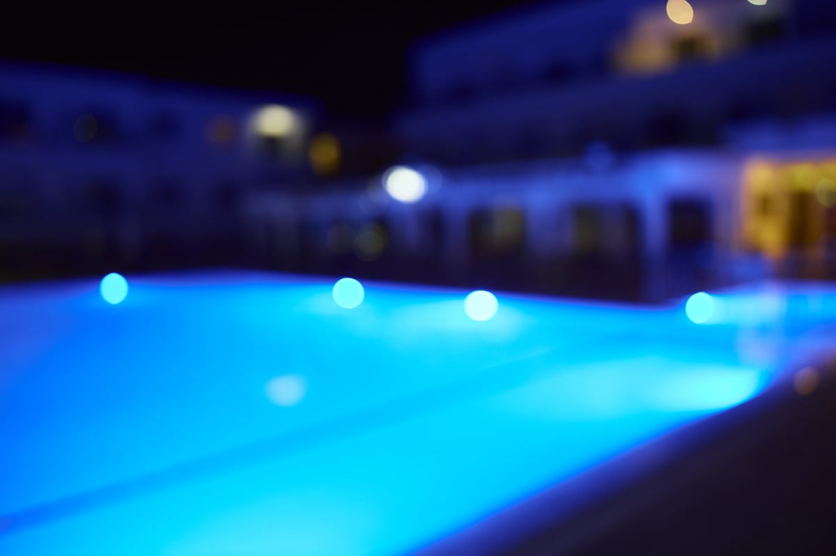 Glowing swimming pool in a luxury resort at night with blue illuminated water